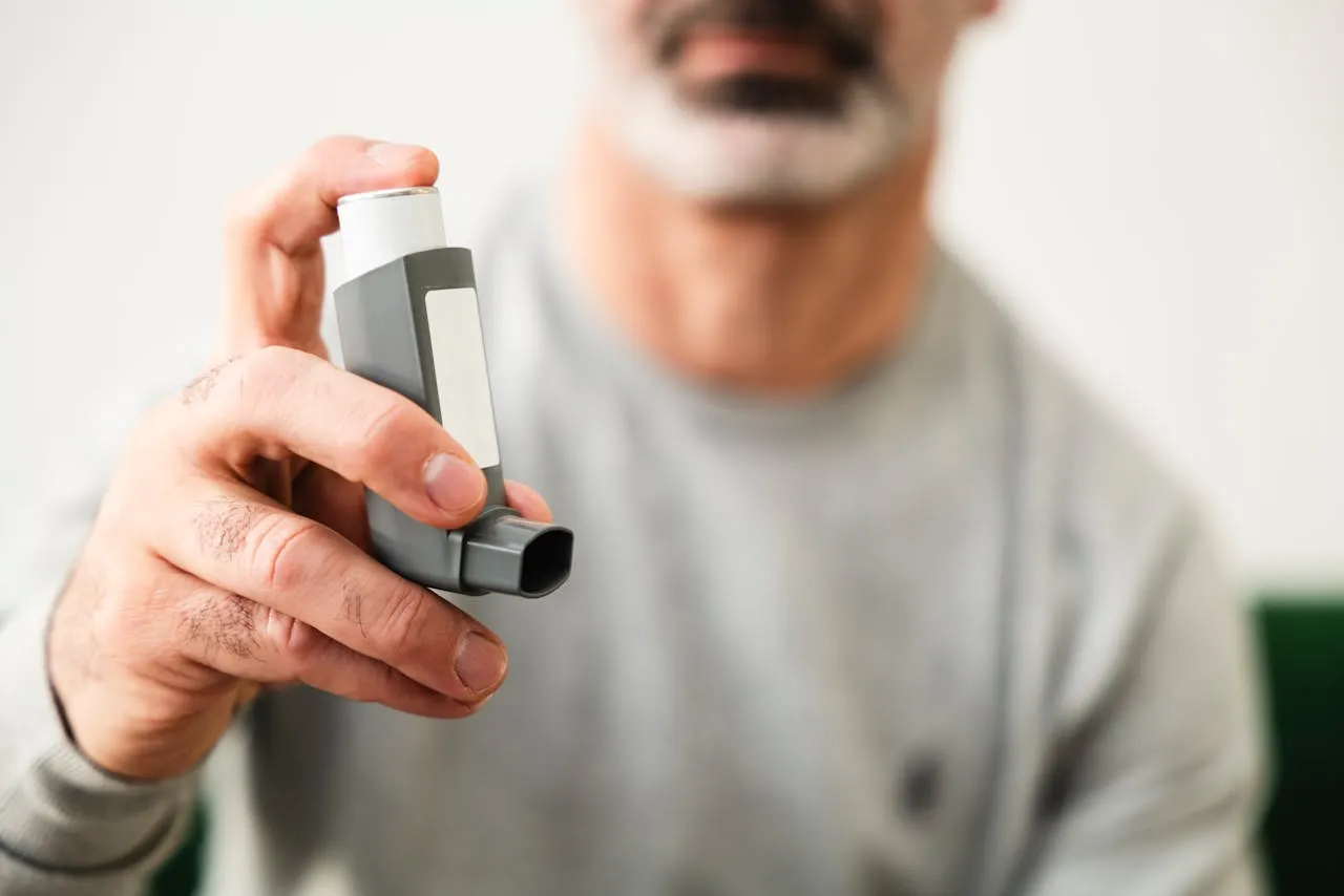 Man holding an asthma inhaler in a casual setting.